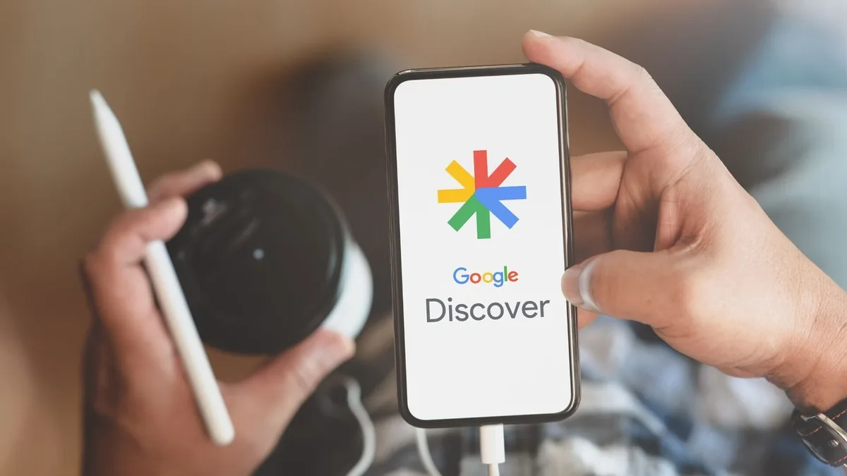 Telefon z logo Google Discover na ekranie, trzymany w dłoni